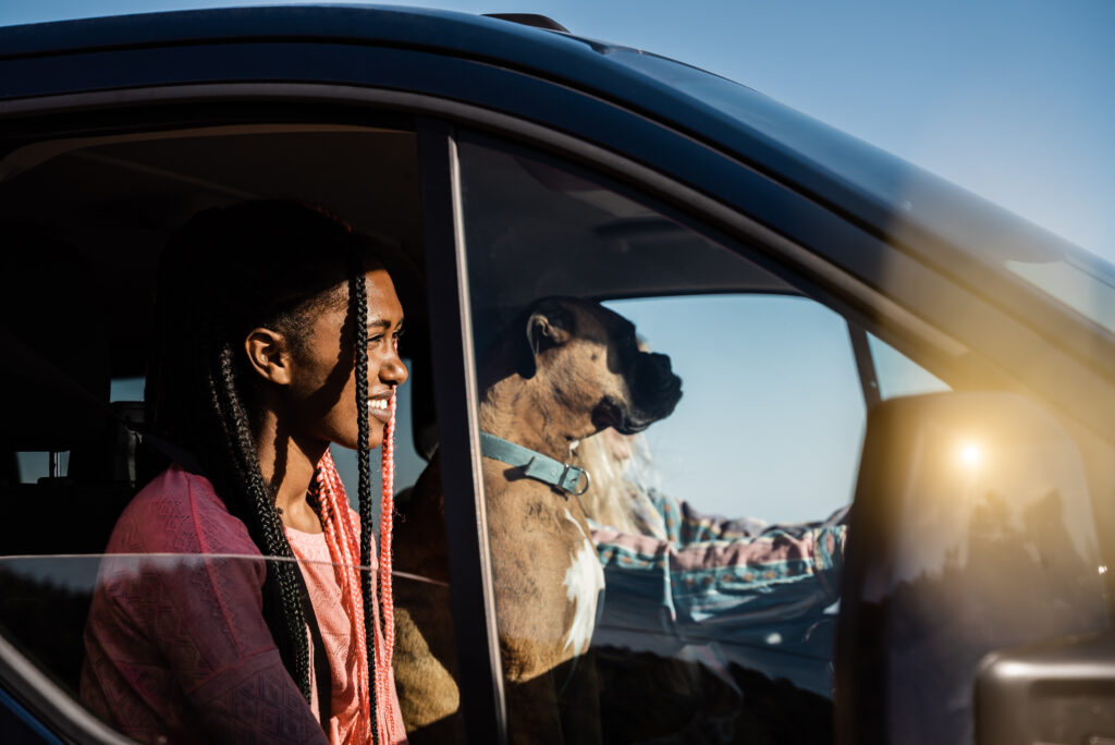 Young multiracial girls and dog having fun on the road inside camper van - Focus on african woman face