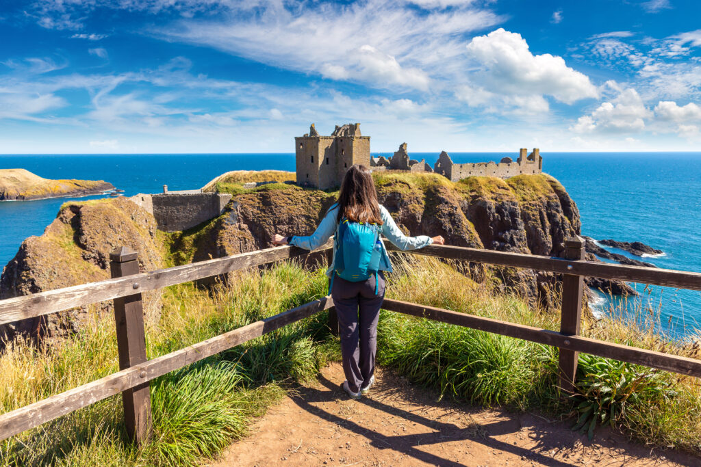 Female hiker at Dunnottar Castle ruins on sea cliffs near Stonehaven, Aberdeenshire, Scotland, UK